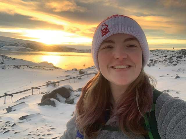 吉拉·伍兹站在日出的雪景前